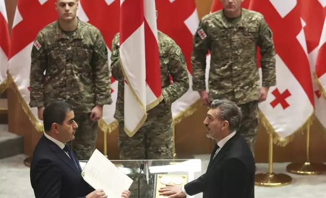 Georgian President-elect Mikheil Kavelashvili, right, takes the oath during his swearing-in ceremony at the Georgian parliament in Tbilisi, Georgia, Sunday, Dec. 29, 2024. (Irakli Gedenidze/Pool Photo via AP)