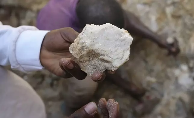 A man shows lithium stone from an illegal mining site in Paseli, north central Nigeria, Tuesday, Nov 5, 2024. (AP Photo/Sunday Alamba)