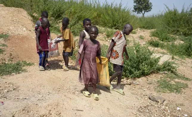 Juliet Samaniya, 6, carries a bag of lithium with other children at an illegal mining site in Paseli, Nigeria, Tuesday, Nov 5, 2024. (AP Photo/Sunday Alamba)