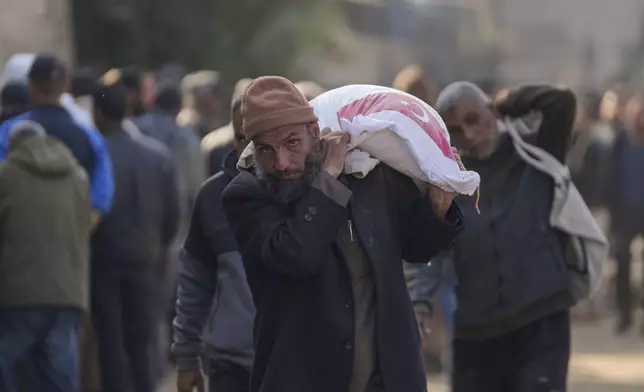 A man carries a sack of donated flour at a UNRWA distribution center in the Nuseirat refugee camp, Gaza Strip, Tuesday Dec. 3, 2024.(AP Photo/Abdel Kareem Hana)