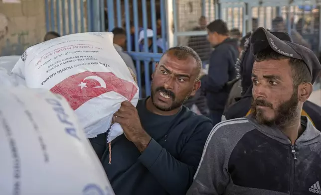 A man grabs a sack of donated flour at a UNRWA distribution center in the Nuseirat refugee camp, Gaza Strip, Tuesday Dec. 3, 2024.(AP Photo/Abdel Kareem Hana)