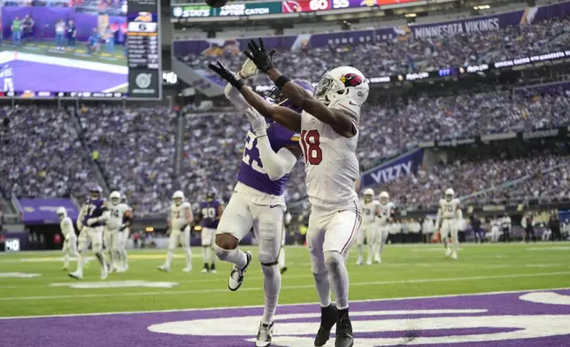 Arizona Cardinals wide receiver Marvin Harrison Jr. (18) catches a 15-yard touchdown pass over Minnesota Vikings cornerback Fabian Moreau (23) during the second half of an NFL football game Sunday, Dec. 1, 2024, in Minneapolis. (AP Photo/Abbie Parr)