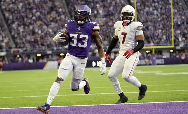 Minnesota Vikings running back Aaron Jones (33) catches a 5-yard touchdown pass in front of Arizona Cardinals linebacker Kyzir White (7) during the second half of an NFL football game Sunday, Dec. 1, 2024, in Minneapolis. (AP Photo/Abbie Parr)