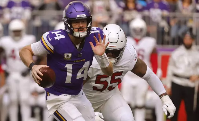 Minnesota Vikings quarterback Sam Darnold (14) runs from Arizona Cardinals defensive tackle Dante Stills (55) during the second half of an NFL football game Sunday, Dec. 1, 2024, in Minneapolis. (AP Photo/Bruce Kluckhohn)