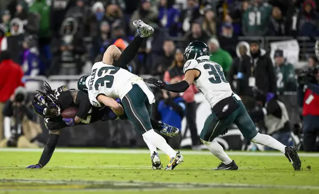 Baltimore Ravens running back Derrick Henry, left, is brought down by Philadelphia Eagles cornerback Cooper DeJean (33) and safety Tristin McCollum (36) during the second half of an NFL football game, Sunday, Dec. 1, 2024, in Baltimore. (AP Photo/Nick Wass)