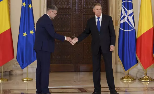 Romanian President Klaus Iohannis, right, shakes hands with Prime Minister designate Marcel Ciolacu, left, after nominating him to form the new government in Bucharest, Romania, Monday, Dec. 23, 2024. (AP Photo/Vadim Ghirda)