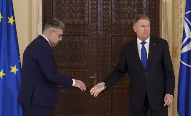 Romanian President Klaus Iohannis, right, walks after shaking hands with Prime Minister designate Marcel Ciolacu, left, after nominating him to form the new government in Bucharest, Romania, Monday, Dec. 23, 2024. (AP Photo/Vadim Ghirda)