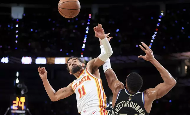 Atlanta Hawks guard Trae Young (11) collides with Milwaukee Bucks forward Giannis Antetokounmpo, right, while contesting for a rebound during the first half of a semifinal game in the NBA Cup basketball tournament Saturday, Dec. 14, 2024, in Las Vegas. (AP Photo/Ian Maule)