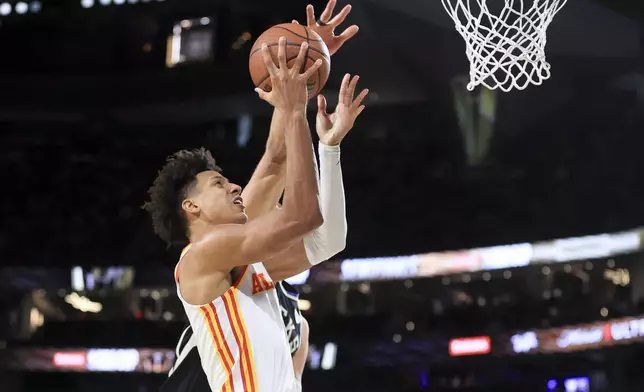 Atlanta Hawks forward Jalen Johnson, front, goes up to shoot against Milwaukee Bucks center Brook Lopez, back, during the first half of a semifinal game in the NBA Cup basketball tournament Saturday, Dec. 14, 2024, in Las Vegas. (AP Photo/Ian Maule)