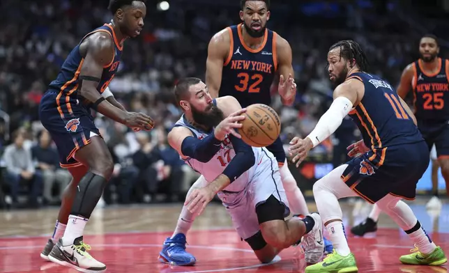 Washington Wizards center Jonas Valanciunas (17) passes the loose ball away from New York Knicks forward OG Anunoby, left, center Karl-Anthony Towns (32) and guard Jalen Brunson (11) during the first half of an NBA basketball game, Monday, Dec. 30, 2024, in Washington. (AP Photo/Terrance Williams)