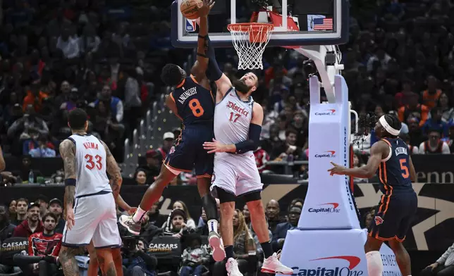 New York Knicks forward OG Anunoby (8) has his shot blocked by Washington Wizards center Jonas Valanciunas (17) during the first half of an NBA basketball game, Monday, Dec. 30, 2024, in Washington. (AP Photo/Terrance Williams)