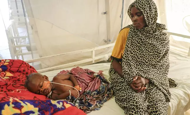 Khadiga Omer adam sits by her sick child in an MSF-run clinic in the Aboutengue displacement site near Acre, Chad, Friday, Oct 4. 2024. (AP Photo/Sam Mednick)