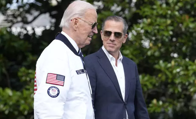 FILE - President Joe Biden, wearing a Team USA jacket and walking with his son Hunter Biden, heads toward Marine One on the South Lawn of the White House in Washington, July 26, 2024. (AP Photo/Susan Walsh, File)