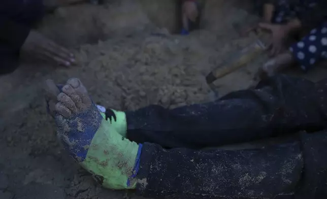 One of Reda Abu Zarada's grandchildren, displaced from Jabaliya in northern Gaza, sits on the dirt wearing torn socks while playing near their tent at a camp in Khan Younis, Gaza Strip, Thursday Dec. 19, 2024. (AP Photo/Abdel Kareem Hana)