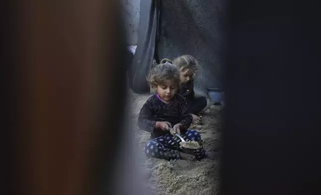 Grandchildren of Reda Abu Zarada, displaced from Jabaliya in northern Gaza, play with sand next to their tent at a camp in Khan Younis, Gaza Strip, Thursday, Dec. 19, 2024. (AP Photo/Abdel Kareem Hana)