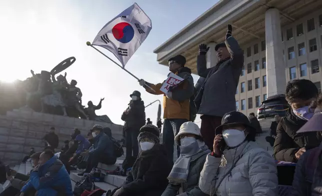 A protester waves a South Korean flag as he joins others gathering outside the National Assembly in Seoul, South Korea, Wednesday, Dec. 4, 2024. (AP Photo/Ng Han Guan)