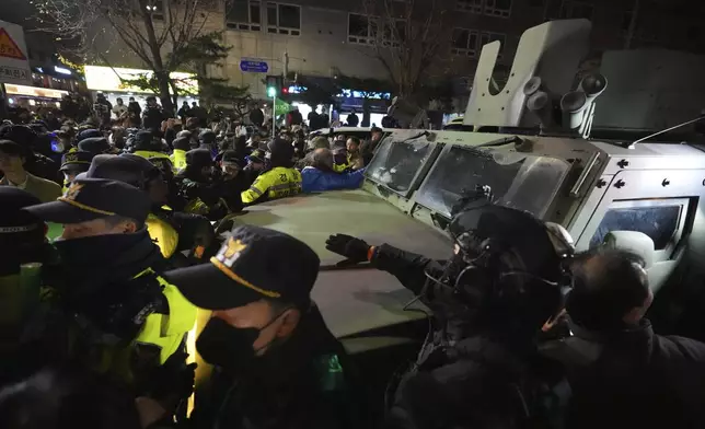 Military vehicle is escorted by police officers as people try to block outside of the National Assembly in Seoul, South Korea, Wednesday, Dec. 4, 2024. (AP Photo/Lee Jin-man)