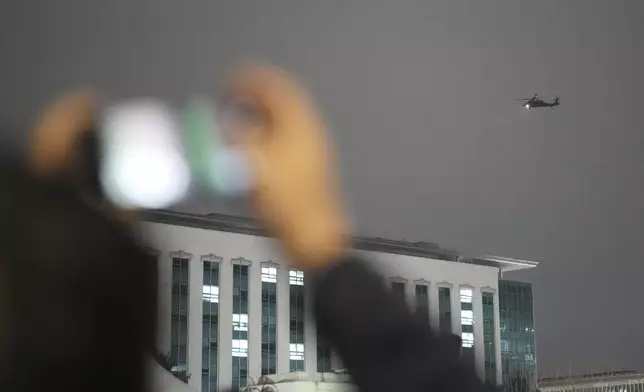 A helicopter flies over the National Assembly in Seoul, South Korea, Wednesday, Dec. 4, 2024. (AP Photo/Lee Jin-man)