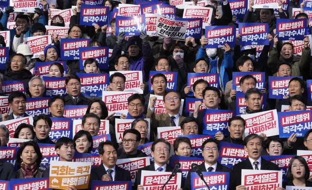 South Korea's main opposition Democratic Party leader Lee Jae-myung, bottom center, shout slogans during a rally against President Yoon Suk Yeol at the National Assembly in Seoul, South Korea, Wednesday, Dec. 4, 2024. The signs read "Yoon Suk Yeol should resign." (AP Photo/Ahn Young-joon)