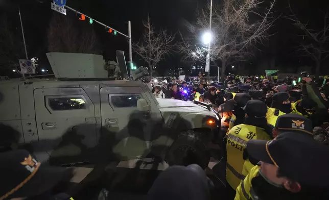 Military vehicle is escorted by police officers as people try to block outside of the National Assembly in Seoul, South Korea, Wednesday, Dec. 4, 2024. (AP Photo/Lee Jin-man)