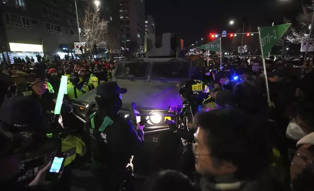 Military vehicle is escorted by police officers as people try to block outside of the National Assembly in Seoul, South Korea, Wednesday, Dec. 4, 2024. (AP Photo/Lee Jin-man)