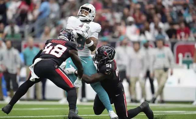 Miami Dolphins tight end Jonnu Smith (9) gets tackled by Houston Texans defensive end Will Anderson Jr. (51) as linebacker Christian Harris (48) pressures, during the first half of an NFL football game Sunday, Dec. 15, 2024, in Houston. (AP Photo/Ashley Landis)