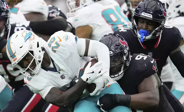 Miami Dolphins running back De'Von Achane (28) is tackled by Houston Texans defensive tackle Folorunso Fatukasi (91) during the first half of an NFL football game Sunday, Dec. 15, 2024, in Houston. (AP Photo/Ashley Landis)