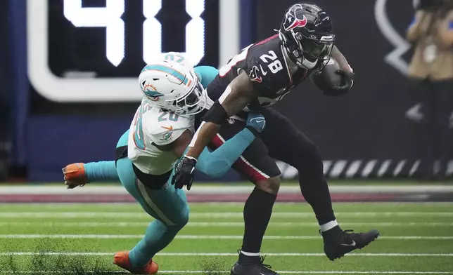 Houston Texans running back Joe Mixon (28) is tackled by Miami Dolphins linebacker Jordyn Brooks (20) during the first half of an NFL football game Sunday, Dec. 15, 2024, in Houston. (AP Photo/Ashley Landis)