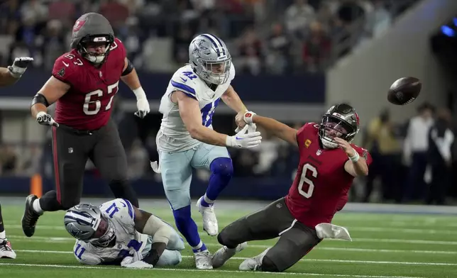 Dallas Cowboys linebacker Micah Parsons (11) strips the ball away from Tampa Bay Buccaneers quarterback Baker Mayfield (6) as Nick Vigil (41) attempts to recover the ball that fell out-of-bounds in the second half of an NFL football game in Arlington, Texas, Sunday, Dec. 22, 2024. (AP Photo/Jeffrey McWhorter)