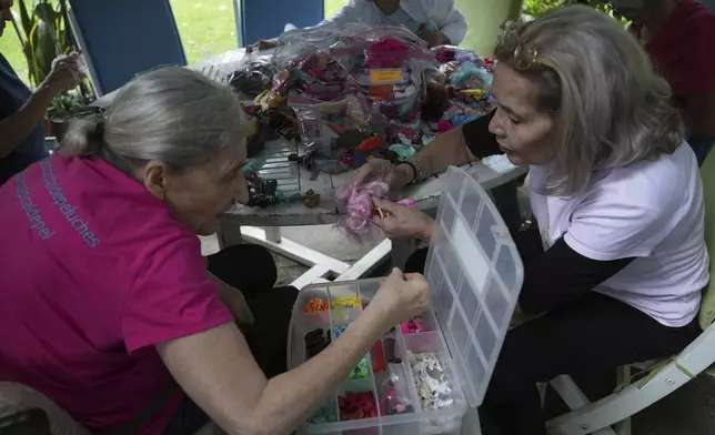 A volunteer looks through a selection of miniature doll shoes at the non-profit foundation Hospital de los Peluches, or Hospital of Stuffed Animals, where used toys are recycled and restored to donate them to vulnerable children as Christmas presents, in Caracas, Venezuela, Thursday, Dec. 5, 2024. (AP Photo/Ariana Cubillos)
