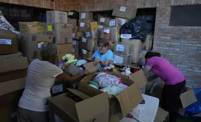Volunteers organize boxes of used toys at the non-profit foundation Hospital de los Peluches, or Hospital of Stuffed Animals, where recycled toys are restored to be donated to vulnerable children as Christmas presents, in Caracas, Venezuela, Thursday, Dec. 5, 2024. (AP Photo/Ariana Cubillos)