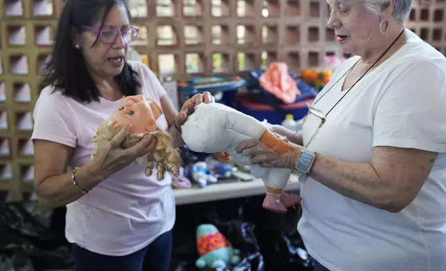 Volunteers Aides Jimenez, left, and Miriam Goodman, discuss the best way to restore a recycled doll at the non-profit foundation Hospital de los Peluches, or Hospital of Stuffed Animals, in Caracas, Venezuela, Thursday, Dec. 5, 2024. (AP Photo/Ariana Cubillos)