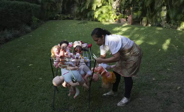Irelis Baldirio hangs laundered used dolls to dry at the non-profit foundation Hospital de los Peluches, or Hospital of Stuffed Animals, where recycled toys are restored to be donated to vulnerable children as Christmas presents, in Caracas, Venezuela, Thursday, Dec. 5, 2024. (AP Photo/Ariana Cubillos)