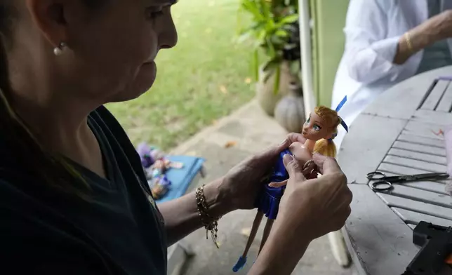 A volunteer dresses a used doll at the non-profit foundation Hospital de los Peluches, or Hospital of Stuffed Animals, where recycled toys are restored to be donated to vulnerable children as Christmas presents, in Caracas, Venezuela, Thursday, Dec. 5, 2024. (AP Photo/Ariana Cubillos)