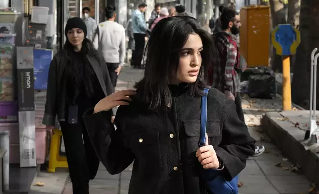 An Iranian woman, without wearing her mandatory Islamic headscarf, walks in northern Tehran, Iran, Friday, Nov. 15, 2024. (AP Photo/Vahid Salemi)