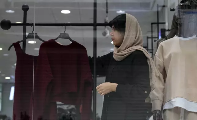 A shopkeeper puts on a woman's clothes on a mannequin at a shop in port city of Bandar Anzali in northern Iran, Thursday, Dec. 5, 2024. (AP Photo/Vahid Salemi)