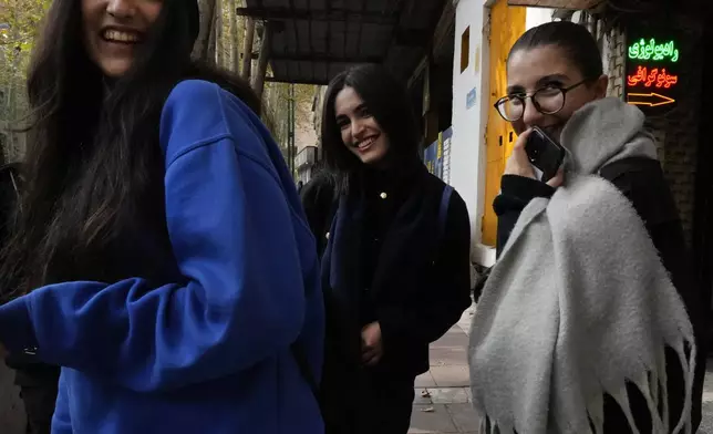 Iranian women, without wearing their mandatory Islamic headscarves, share a laugh while walking in northern Tehran, Iran, Friday, Nov. 15, 2024. (AP Photo/Vahid Salemi)