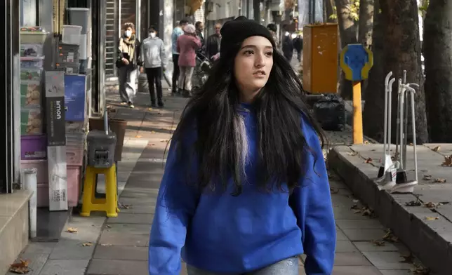 An Iranian woman, without wearing her mandatory Islamic headscarf, walks in northern Tehran, Iran, Friday, Nov. 15, 2024. (AP Photo/Vahid Salemi)