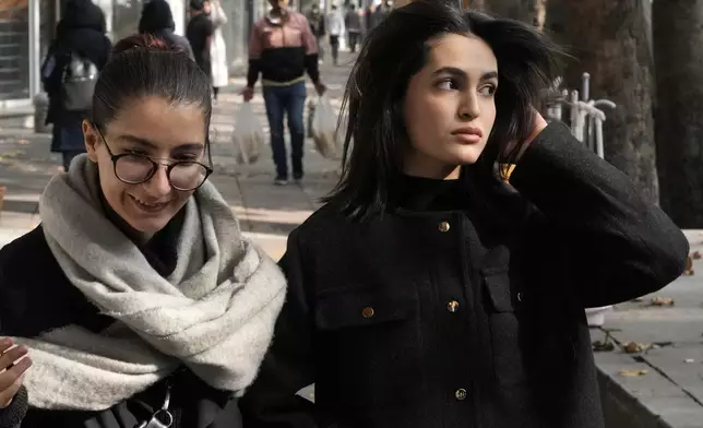 Iranian women, without wearing their mandatory Islamic headscarves, walk in northern Tehran, Iran, Friday, Nov. 15, 2024. (AP Photo/Vahid Salemi)