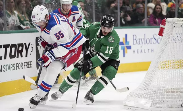 New York Rangers defenseman Ryan Lindgren (55) works to take control of the puck while under pressure from Dallas Stars center Sam Steel (18) in the first period of an NHL hockey game in Dallas, Friday, Dec. 20, 2024. (AP Photo/Tony Gutierrez)