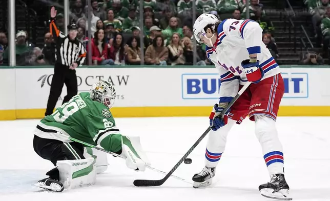 Dallas Stars goaltender Jake Oettinger (29) slaps the puck away on an attack by New York Rangers' Matt Rempe (73) in the second period of an NHL hockey game in Dallas, Friday, Dec. 20, 2024. (AP Photo/Tony Gutierrez)