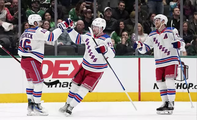 New York Rangers' Vincent Trocheck (16), Alexis Lafrenière (13) and Adam Fox, right, celebrate Trocheck's score against the Dallas Stars in the first period of an NHL hockey game in Dallas, Friday, Dec. 20, 2024. (AP Photo/Tony Gutierrez)