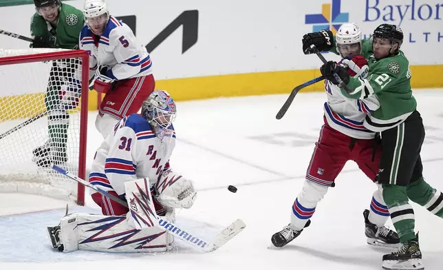 New York Rangers goaltender Igor Shesterkin (31) prepares to block a shot as defenseman Braden Schneider (4) helps against pressure by Dallas Stars left wing Jason Robertson (21) in the third period of an NHL hockey game in Dallas, Friday, Dec. 20, 2024. (AP Photo/Tony Gutierrez)