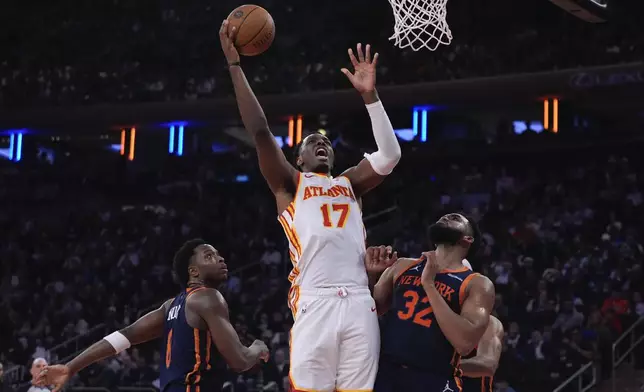 Atlanta Hawks' Onyeka Okongwu (17) shoots over New York Knicks' Karl-Anthony Towns (32) and OG Anunoby (8) during the first half of an Emirates NBA Cup basketball game Wednesday, Dec. 11, 2024, in New York. (AP Photo/Frank Franklin II)