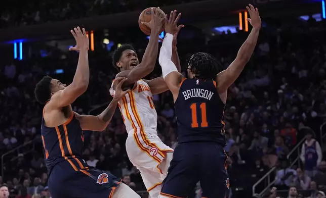 New York Knicks' Karl-Anthony Towns (32) and Jalen Brunson (11) defend Atlanta Hawks' De'Andre Hunter (12) during the first half of an Emirates Cup NBA basketball game Wednesday, Dec. 11, 2024, in New York. (AP Photo/Frank Franklin II)