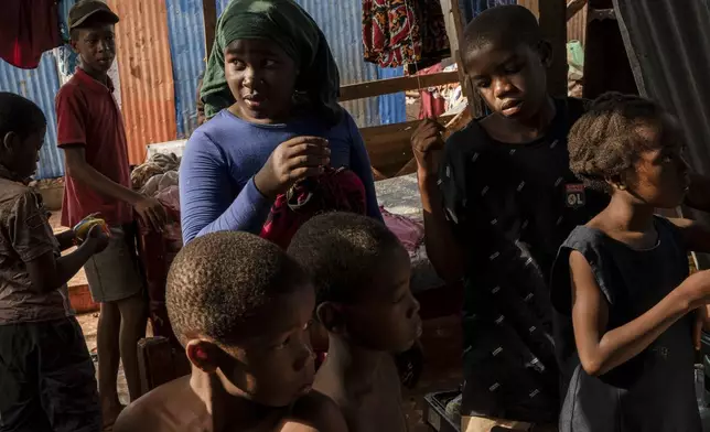 Children stand in the half destroyed house of Zaharia Youssouf in Barakani, Mayotte, Saturday, Dec. 21, 2024. (AP Photo/Adrienne Surprenant)