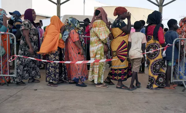 Women wait in line at a water distribution point in Mamoudzou, Mayotte, Saturday, Dec. 21, 2024. (AP Photo/Adrienne Surprenant)