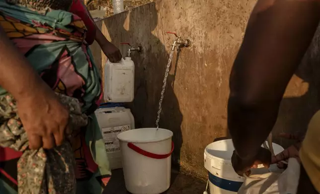 People line up to collect water in Barakani, Mayotte, home Saturday, Dec. 21, 2024. (AP Photo/Adrienne Surprenant)