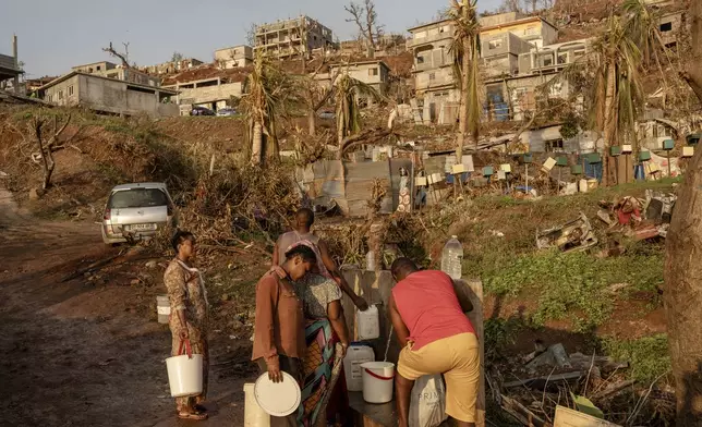 People line up to collect water in Barakani, Mayotte, home Saturday, Dec. 21, 2024. (AP Photo/Adrienne Surprenant)