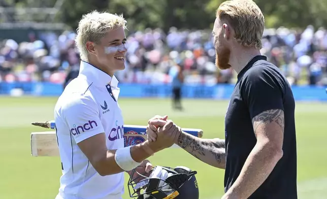 England's Jacob Bethell, left, is congratulated by his captain Ben Stokes following their eight wicket win in the first cricket test against New Zealand at Hagley Oval in Christchurch, New Zealand, Sunday, Dec. 1, 2024.(John Davidson/Photosport via AP)